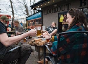 People enjoying drinks outdoors together around a fire at Lookout Brewing.